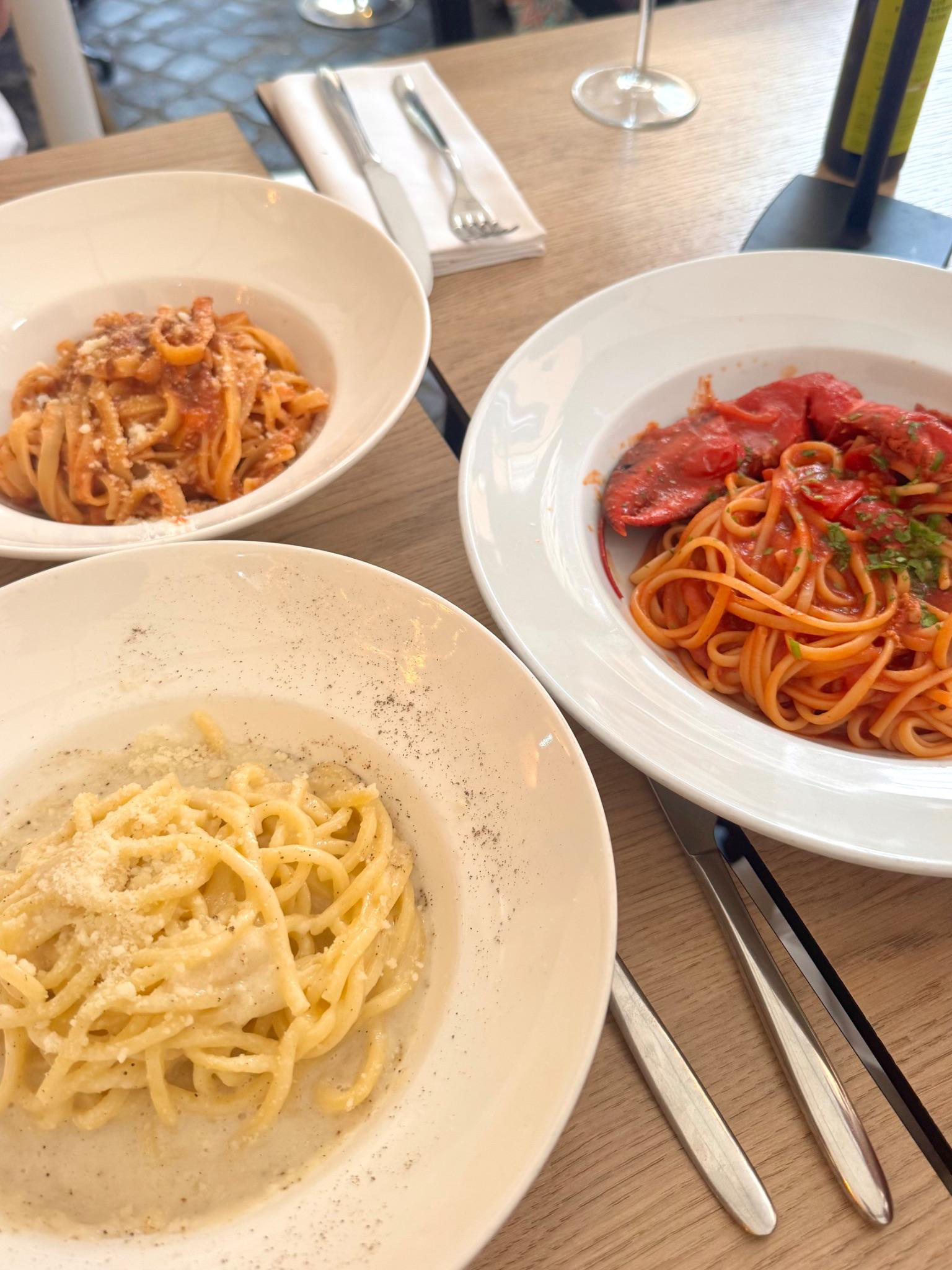 Three plates of pasta on the patio at Osteria Pasquino