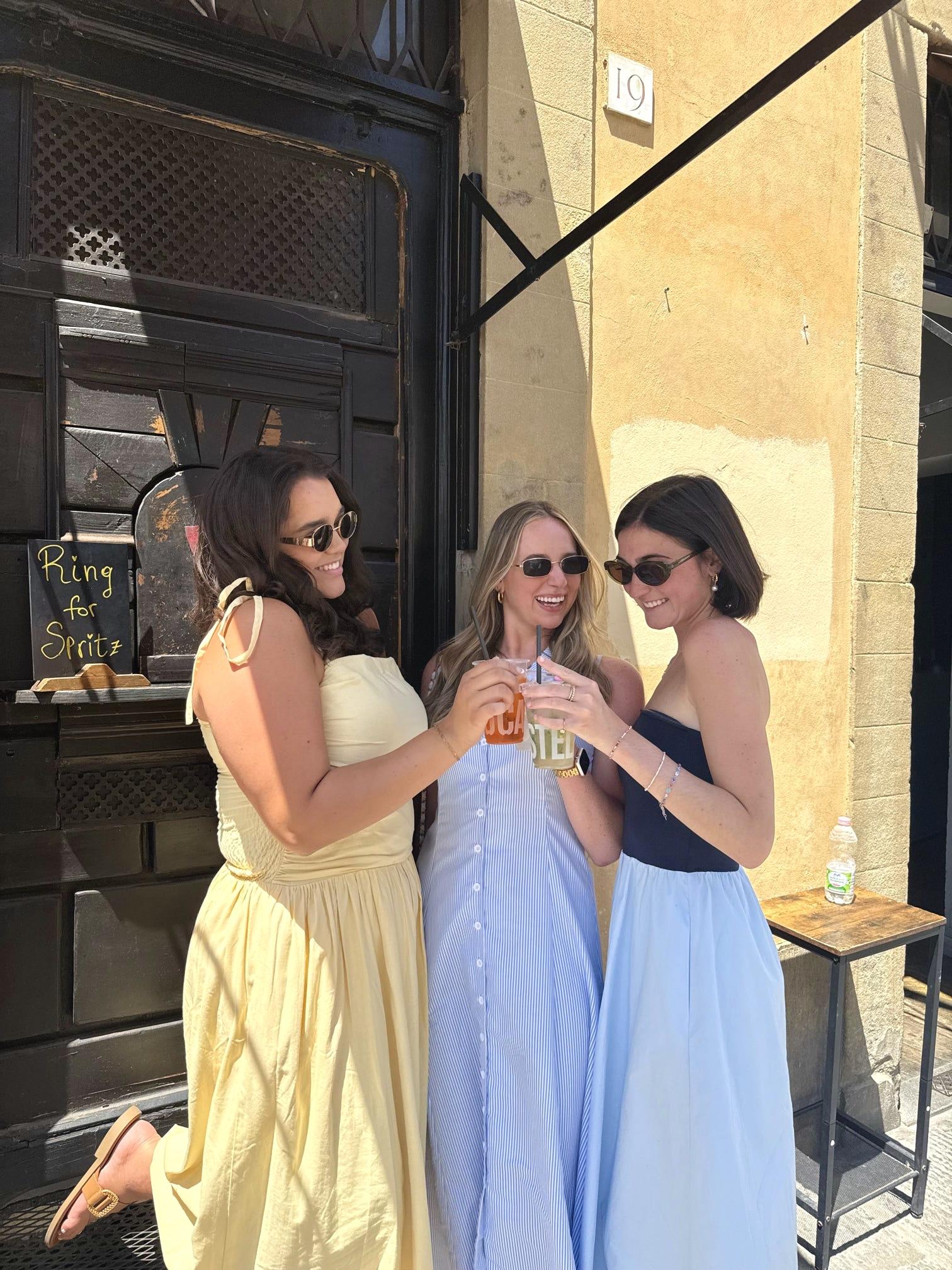 Three of us toasting spritzes outside a window that reads Ring for Spritz
